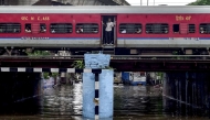 A train crosses over a flooded railway bridge during heavy rainfall in Jalandhar on August 14, 2025. (Photo by Shammi MEHRA / AFP)