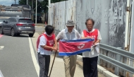 Ahn Hak-sop (C), a former North Korean soldier, holds a North Korean flag near a military checkpoint on the Tongil bridge in the border city of Paju on August 20, 2025. (Photo by YONHAP / AFP) 