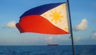 This handout photo taken April 14, 2021, and received from the Philippine Coast Guard (PCG) April 15, a Philippine flag is displayed aboard a coast guard rubber boat as they patrol past Chinese vessels at Whitsun Reef, in the Spratly Islands. Photo by Philippine coast Guard (PCG) / AFP.