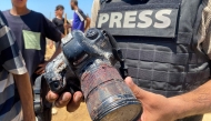 A journalist holds the blood-covered camera belonging to Palestinian photojournalist Mariam Dagga, a journalist who freelanced for AP since the start of the war and who was killed in an Israeli strike on Nasser hospital in Khan Yunis in the southern Gaza Strip, during her funeral on August 25, 2025. Photo by AFP