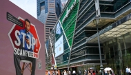 People walk past a poster warning of scam threats in the financial business district of Raffles Place in Singapore on September 3, 2025. Photo by Roslan RAHMAN / AFP