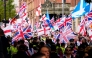 Supporters of British far-right activist Tommy Robinson whose real name is Stephen Yaxley-Lennon, walk through central London waving flags during a 'Free speech' march, on September 13, 2025. (Photo by CARLOS JASSO / AFP)