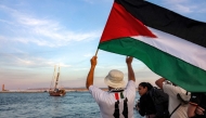 A man waves a Palestinian flags to other activists and human rights defenders riding aboard a vessel departing from Tunisia's northern port of Bizerte on September 14, 2025 to join the last boats taking part in the Global Sumud Flotilla. (Photo by Mohamed Fliss / AFP)