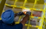 A worker grabs products from a bin at Amazon Fulfillment Center SCK6 in Tracy, California. Photo credit: Jungho Kim/For The Washington Post

