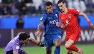 Al Duhail's Adil Boulbina (right) prepares to score a goal against Al Hilal.