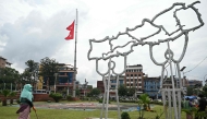 A civic worker walks past Nepal's national flag flying at half-mast next to a structure built in the shape of country's map, in Kathmandu on September 17, 2025. (Photo by Arun Sankar / AFP)