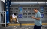 A woman (L) reads a book at a self-service library beside a pavement in Beijing on September 22, 2025. (Photo by WANG Zhao / AFP)