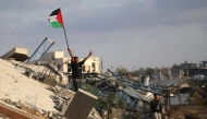 A displaced Palestinian child waves a Palestinian national flag as he stands on the rubble of a destroyed building at the Bureij camp for refugees in the central Gaza Strip on September 22, 2025. (Photo by Eyad Baba / AFP)