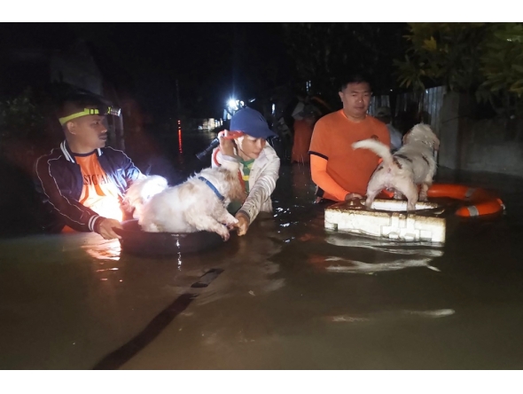 :In this handout photo taken early September 26, 2025 and released by the Philippine Coast Guard (PCG), coast guard personnel evacuate residents along with their pets at the height of Severe Tropical Storm Bualoi in Ormoc City, Leyte province, central Philippines. (Photo by Handout / Philippine Coast Guard (PCG) / AFP)
