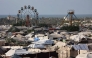 An idle ferris wheel stands near tents at a camp for displaced people in Khan Yunis in the southern Gaza Strip, on September 29, 2025. (Photo by Omar Al-Qattaa / AFP)