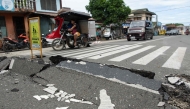 Vehicles maneuver past a damaged part of a road in Bogo City on October 1, 2025, after a powerful 6.9 magnitude earthquake jolted the central Philippines. (Photo by Ted Aljibe / AFP)