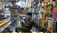 An Afghan vendor selling perfume and body sprays, uses his mobile phone as he sits at his shop in Kabul on October 1, 2025.  (Photo by Wakil Kohsar / AFP)
