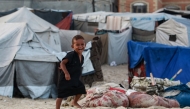 A displaced Palestinian child runs amid tents used as temporary shelter, in Deir el-Balah in the central Gaza Strip, on October 5, 2025. (Photo by Bashar Taleb / AFP)