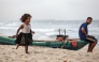 A displaced Palestinian girl runs along the beach as a man sits on a fishing boat, in Deir el-Balah in the central Gaza Strip, on October 5, 2025. (Photo by Bashar TALEB / AFP)
