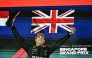 First-placed Mercedes' British driver George Russell celebrates on the podium after the Formula One Singapore Grand Prix night race at the Marina Bay Street Circuit in Singapore on October 5, 2025. (Photo by Lillian SUWANRUMPHA / AFP)