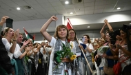 Swedish climate campaigner Greta Thunberg raises her fist, upon arrival alongside activists who were sailing aboard vessels from the Gaza-bound aid flotilla before being stopped and detained by Israeli forces, greeted by a crowd of supporters, at the arrivals area of Athens International Airport on October 6, 2025. (Photo by Aris Messinis / AFP)