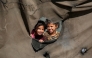 Children look on from a hole behind the canvas of a tent at a camp for people displaced by war in northern Nuseirat in the central Gaza Strip on October 7, 2025. (Photo by Bashar Taleb / AFP)