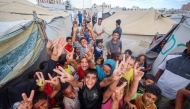 Palestinian children celebrate at a camp for displaced people in Nuseirat in the central Gaza Strip on October 9, 2025, following news of a new peace deal. (Photo by Eyad Baba / AFP)