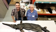 This undated handout image received in London from The University of Manchester on October 10, 2025 shows, Dr Dean Lomax (L) and Professor Judy Massare (R) posing beside the skeleton of the newly named sword dragon ichthyosaur, Xiphodracon goldencapensis, at the Royal Ontario Museum, Toronto, Canada. (Photo by University of Manchester / AFP)