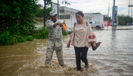A member of the National Guard helps evacuate a woman through a flooded street following heavy rains in Poza Rica, Veracruz state, Mexico, on October 10, 2025. (Photo by Marco Antonio Perez / AFP)