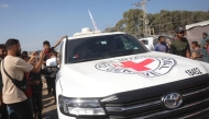 Palestinians gather on both sides of the road as International Red Cross vehicles arrive south of Deir al-Balah in the central Gaza Strip on October 13, 2025. (Photo by Bashar Taleb / AFP)
 
