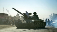 Taliban security personnel on a Soviet-era tank are followed by motorcyclists as they ride towards the border, as clashes take place between Taliban security personnel and Pakistani border forces, in the Spin Boldak district of Kandahar Province on October 15, 2025. (Photo by Sanaullah SEIAM / AFP)
