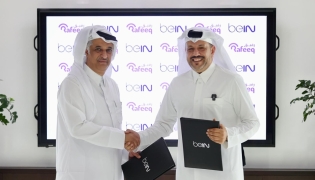beIN Consumer Sales Manager Hamad Aljaber and Rafeeq Media Manager Ahmed Abdulla exchange documents during the ceremony. 