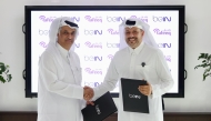 beIN Consumer Sales Manager Hamad Aljaber and Rafeeq Media Manager Ahmed Abdulla exchange documents during the ceremony. 