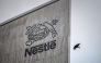 This photograph shows a bird flying next to the logo of Swiss food giant Nestle on the facade of its headquarters, in Vevey, western Switzerland, on October 14, 2025. (Photo by Fabrice Coffrini / AFP)