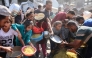 Displaced Palestinians gather to receive food portions outside the damaged Imam al Shafi'i Mosque, where families have taken shelter, in the Zeitoun neighbourhood of Gaza City on October 23, 2025. (Photo by Omar Al-Qattaa / AFP)