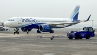 (Files) Ground staff walk past an Indigo airlines aircraft taxiing in the apron at the Netaji Subhash Chandra Bose International airport in Kolkata on February 1, 2024. (Photo by Indranil Mukherjee / AFP)