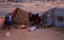 Palestinians sit by the fire in their makeshift shelter in Khan Yunis, in the southern Gaza Strip on October 25, 2025. (Photo by Bashar Taleb / AFP)