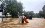 A woman wearing a raincoat wades through a flooded street in Hue on October 28, 2025. Photo by AFP
