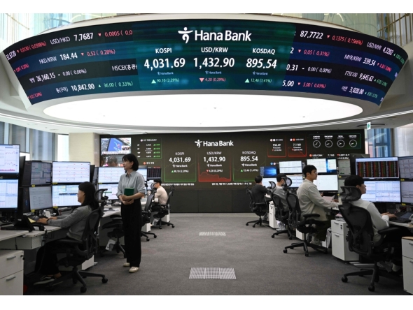 Currency dealers monitor exchange rates in front of a screen showing South Korea's benchmark stock index and the Korean won/USD exchange rate in a foreign exchange dealing room at the Hana Bank headquarters in Seoul on October 27, 2025. (Photo by Jung Yeon-je / AFP)
