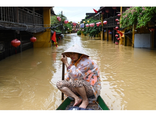 A woman rows a boat on a flooded street following heavy rains in Hoi An on October 30, 2025. (Photo by NHAC NGUYEN / AFP)