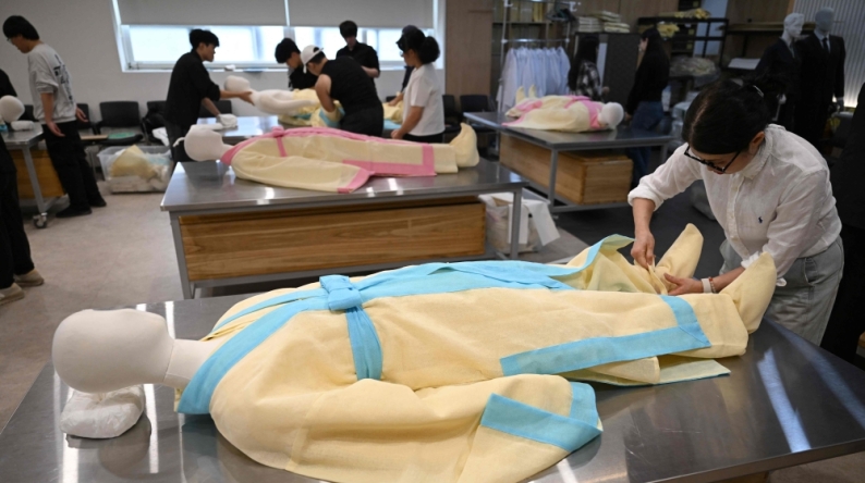 In a photo taken on September 24, 2025, students drape a mannequin in traditional Korean funeral cloth during a funeral administration class in Busan. (Photo by Jung Yeon-je / AFP)