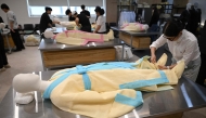 In a photo taken on September 24, 2025, students drape a mannequin in traditional Korean funeral cloth during a funeral administration class in Busan. (Photo by Jung Yeon-je / AFP)