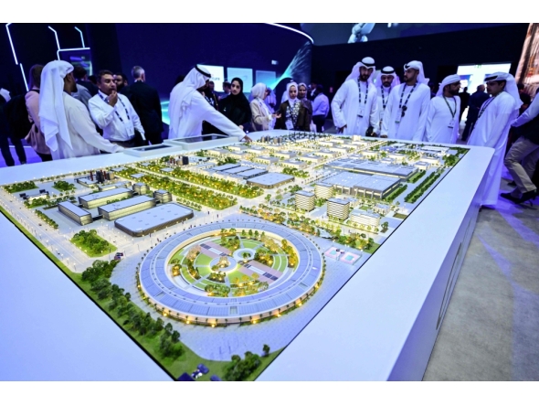 Guests look at a model of the largest data center in the UAE under construction in Abu Dhabi as the Stargate initiative, a joint venture between G42, Microsoft, and OpenAI, during the Abu Dhabi International Petroleum Exhibition & Conference (ADIPEC) in Abu Dhabi on November 3, 2025. (Photo by Giuseppe Cacace / AFP)
