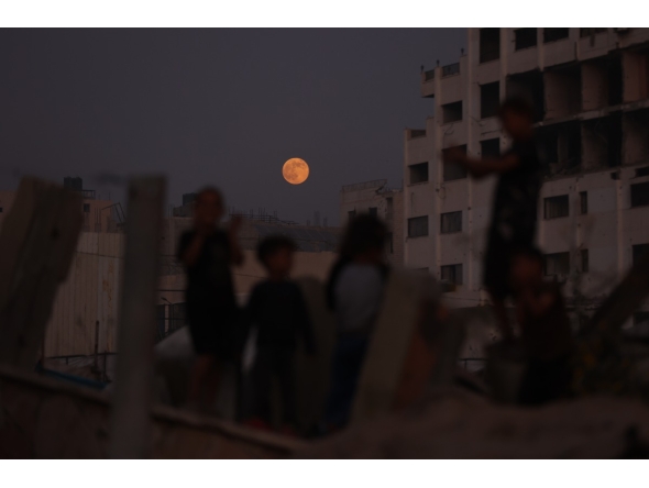 Children play as the moon rises above Gaza City on November 5, 2025. (Photo by Omar AL-QATTAA / AFP)

