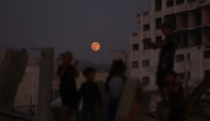 Children play as the moon rises above Gaza City on November 5, 2025. (Photo by Omar AL-QATTAA / AFP)

