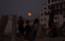 Children play as the moon rises above Gaza City on November 5, 2025. (Photo by Omar AL-QATTAA / AFP)

