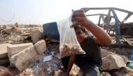 A Palestinian boy shows a bag of seeds and nuts he collected from the sand along the verge of a road near in the Nuseirat refugee camp in the central Gaza Strip, on November 9, 2025. (Photo by Eyad Baba / AFP)