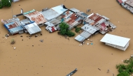 This aerial photo shows a resident paddles his boat in the flood waters past inundated houses in Tuguegarao City, Cagayan province, north of Manila on November 10, 2025, after a river overflowed following heavy rains brought about by Super Typhoon Fung-wong. Photo by JOHN DIMAIN / AFP