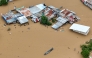 This aerial photo shows a resident paddles his boat in the flood waters past inundated houses in Tuguegarao City, Cagayan province, north of Manila on November 10, 2025, after a river overflowed following heavy rains brought about by Super Typhoon Fung-wong. Photo by JOHN DIMAIN / AFP