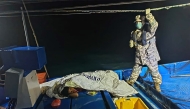 This handout picture taken and released by the Malaysian Maritime Enforcement Agency (MMEA) on November 9, 2025 shows a MMEA staff member checking on a survivor rescued by a fishing boat during a search and rescue operation off the coast of Langkawi, after a boat carrying migrants from Myanmar capsized near the Malaysia-Thailand border. (Photo by Handout / MALAYSIAN MARITIME ENFORCEMENT AGENCY / AFP)