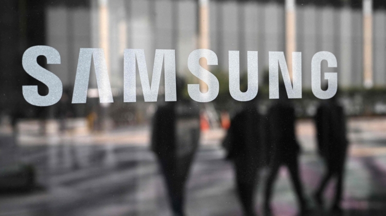 People walk past the Samsung logo displayed on a glass door at the company's Seocho building in Seoul on April 30, 2025. Photo by Jung Yeon-je / AFP