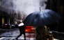 People walk on the street as the rain pours in the Manhattan borough of New York City on November 19, 2025. (Photo by CHARLY TRIBALLEAU / AFP)
