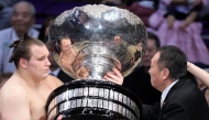 Ukrainian sumo wrestler Danylo Yavhusishyn, also known by his Japanese ring name Aonishiki Arata (L), receives the Prime Minister's Cup trophy after winning the Grand Sumo Tournament in Fukuoka on November 23, 2025. (Photo by JIJI PRESS / AFP) 