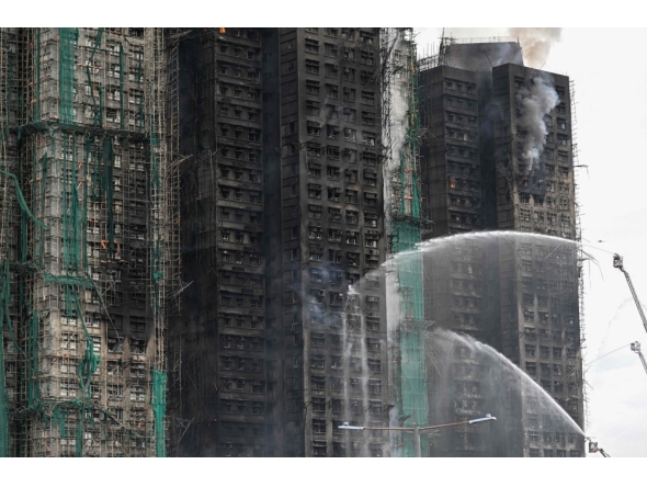 Firefighters spray water on flames as a major fire burns through several apartment blocks at the Wang Fuk Court residential estate on November 27, 2025. (Photo by Peter Parks / AFP)