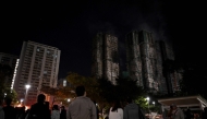 Bystanders look on after a major fire swept through several apartment blocks at the Wang Fuk Court residential estate in Hong Kong's Tai Po district on November 27, 2025. Residents anxiously awaited news of their loved ones on November 27 at a temporary shelter as one of Hong Kong's deadliest fires in decades engulfed a 2,000-unit high-rise complex. (Photo by Philip FONG / AFP)